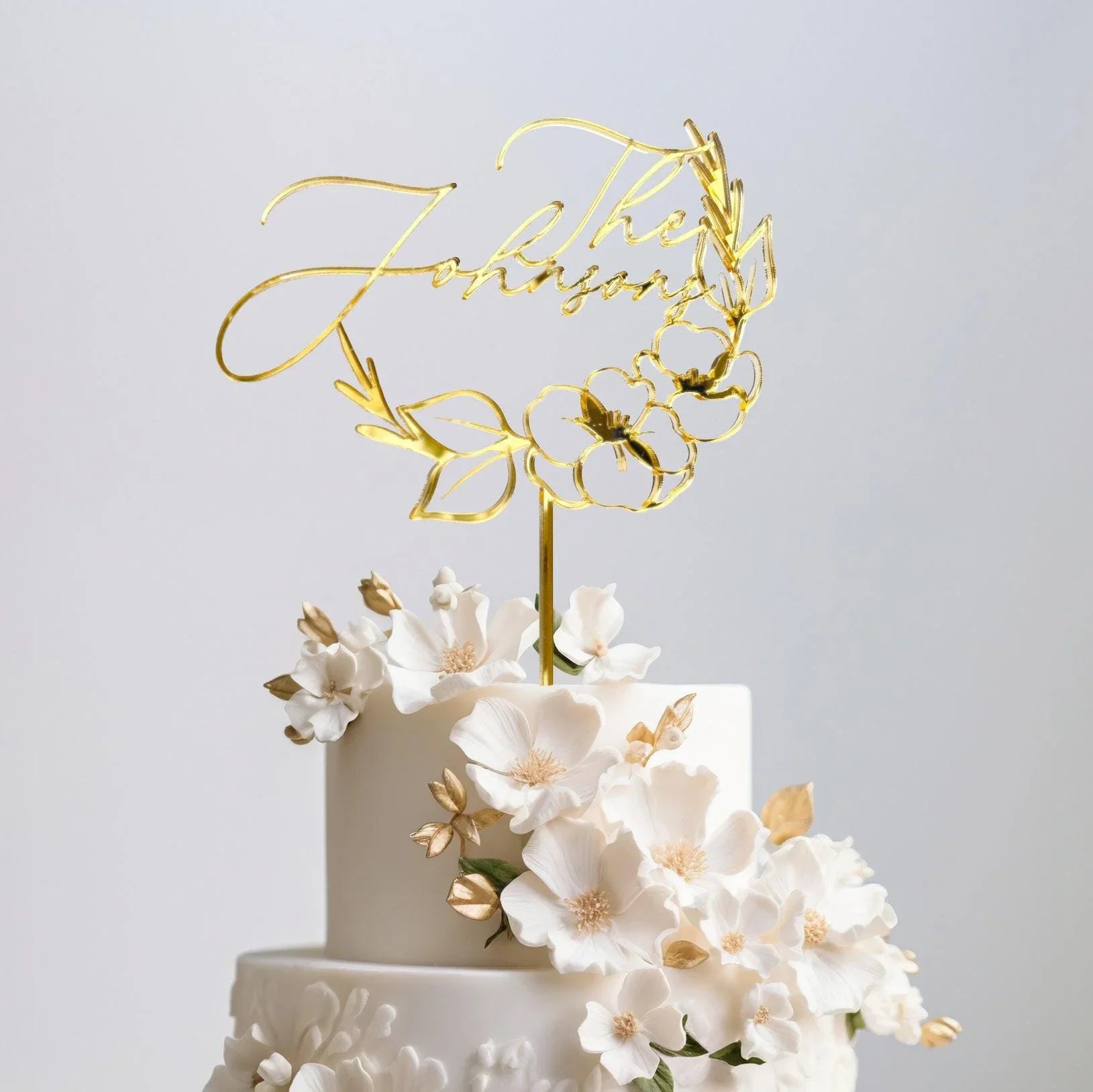Custom acrylic cake topper in gold mirror finish styled on a wedding cake