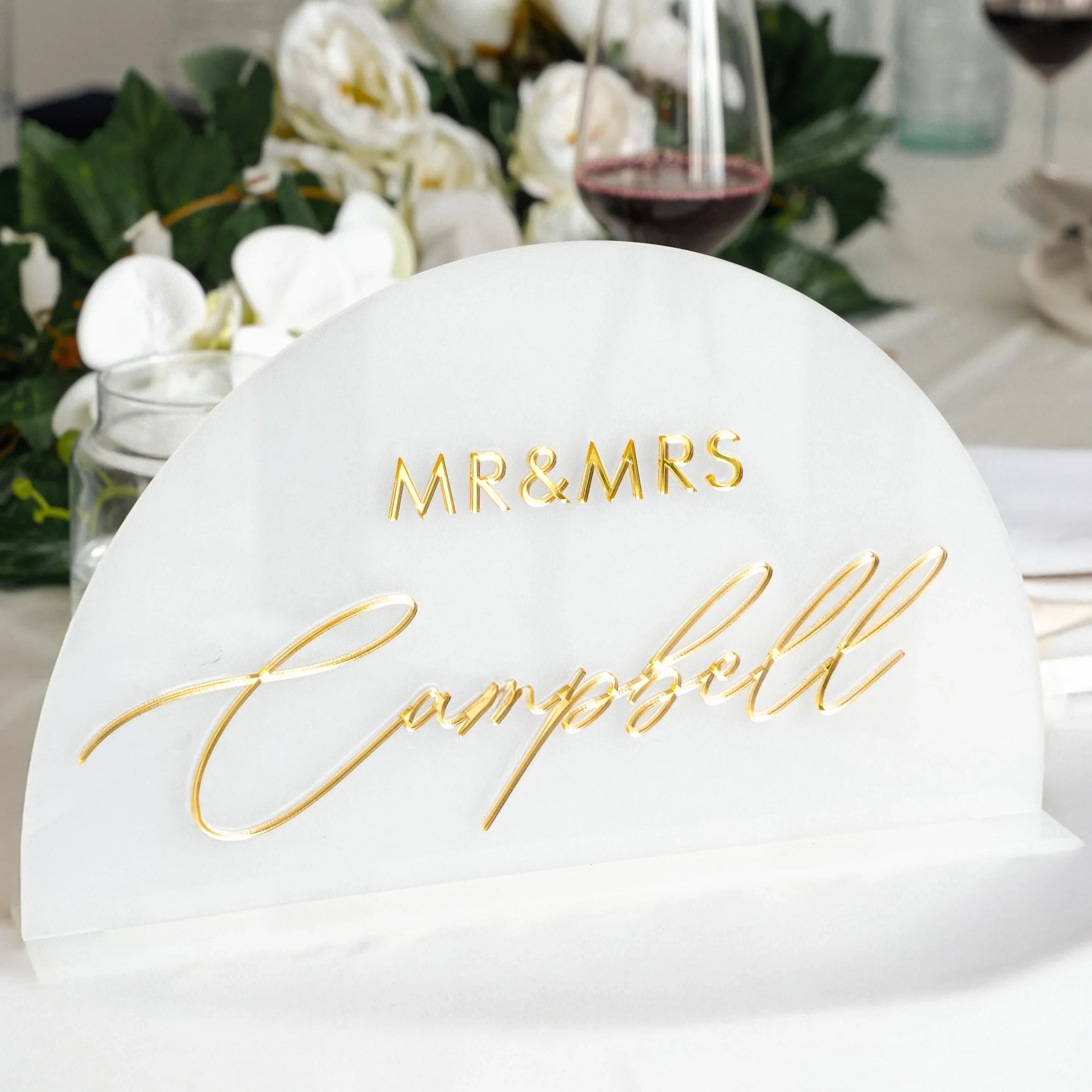 Frosted acrylic sweetheart table name sign with gold lettering styled on a wedding sweetheart table