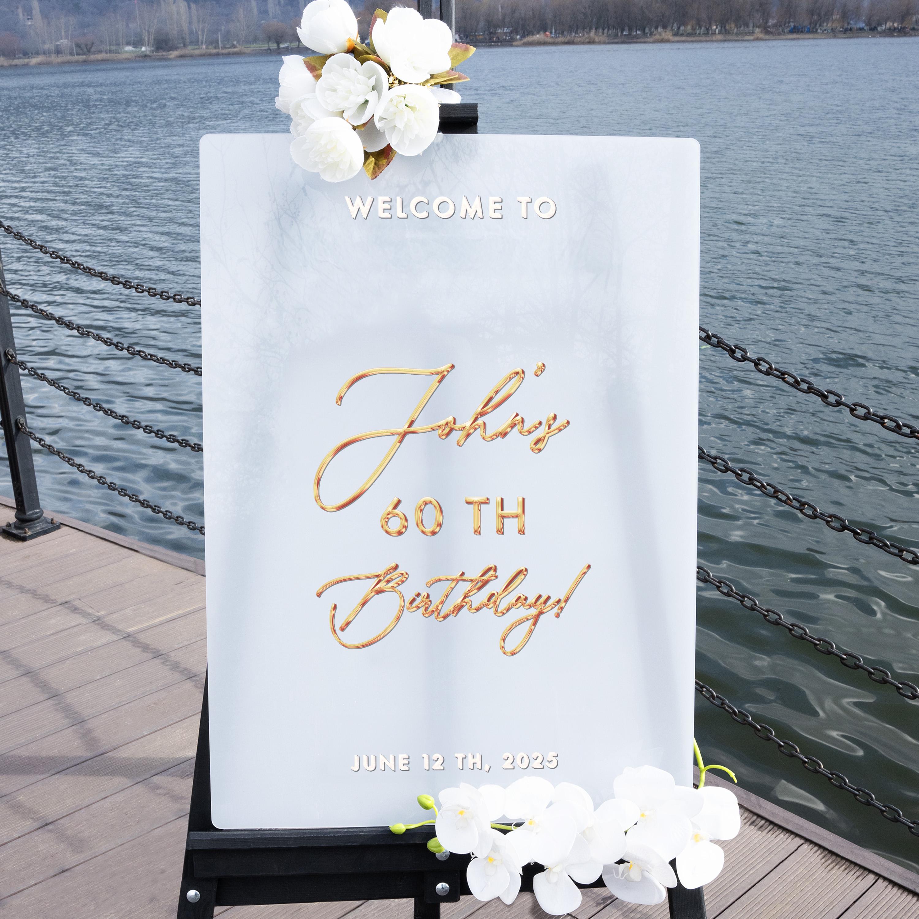 A white sign with gold lettering welcoming guests to a 60th birthday celebration.
