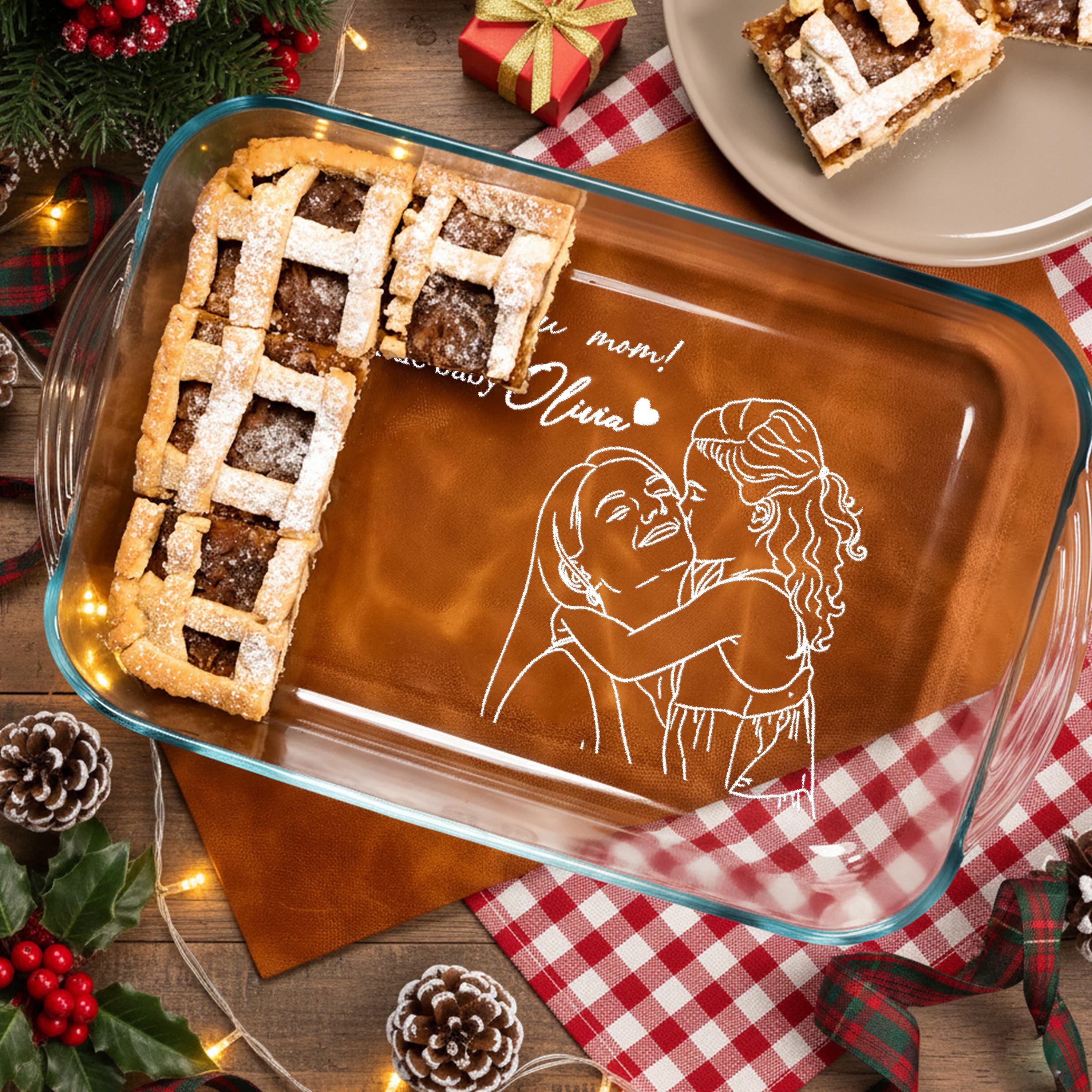 A glass baking dish with a pie on it, surrounded by holiday decorations such as pine cones, berries, and a Christmas tree.