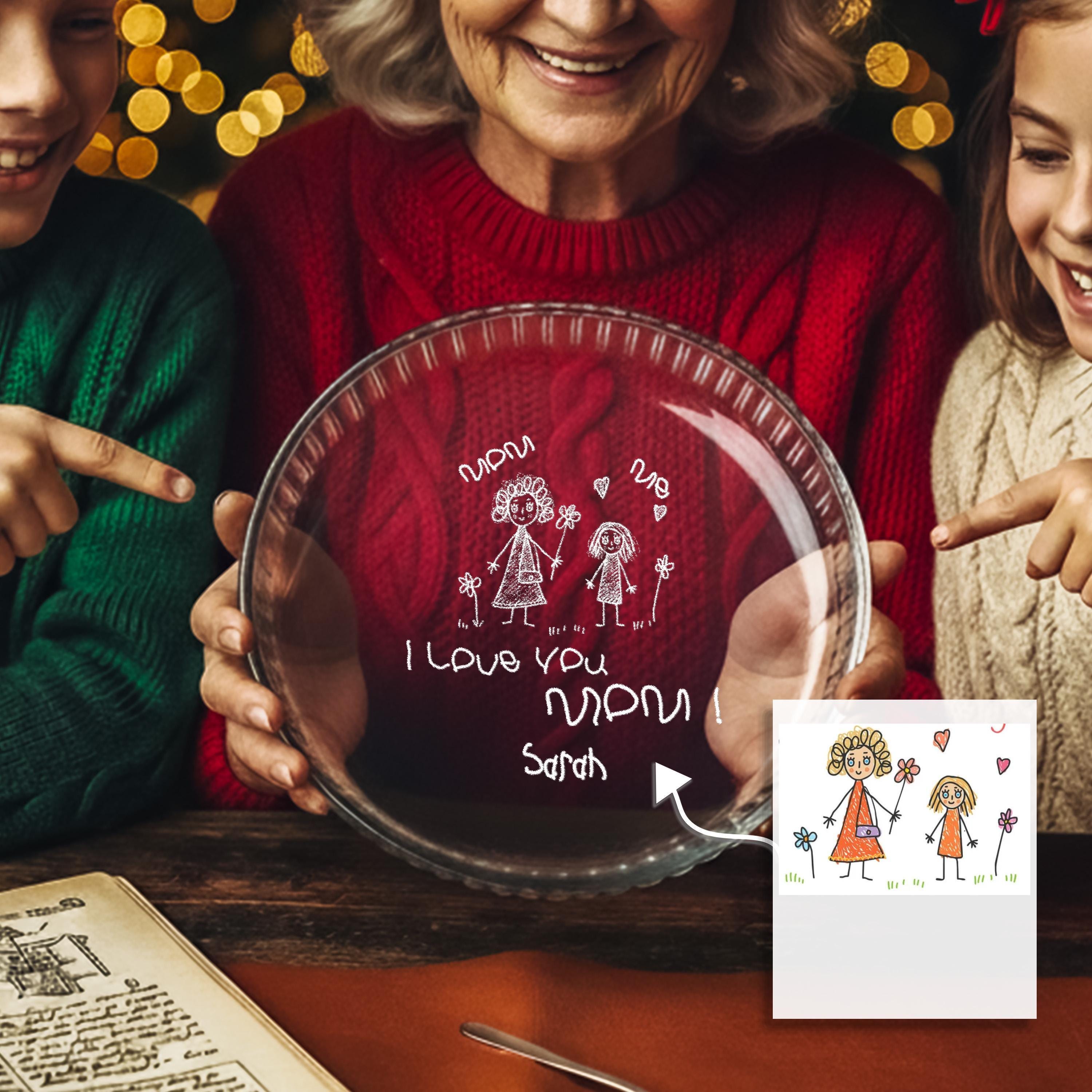 An elderly woman is holding a glass plate with a drawing of two children and the text "I love you Sarah" written on it. The plate is placed on a table, and there is a drawing of two children next to it.