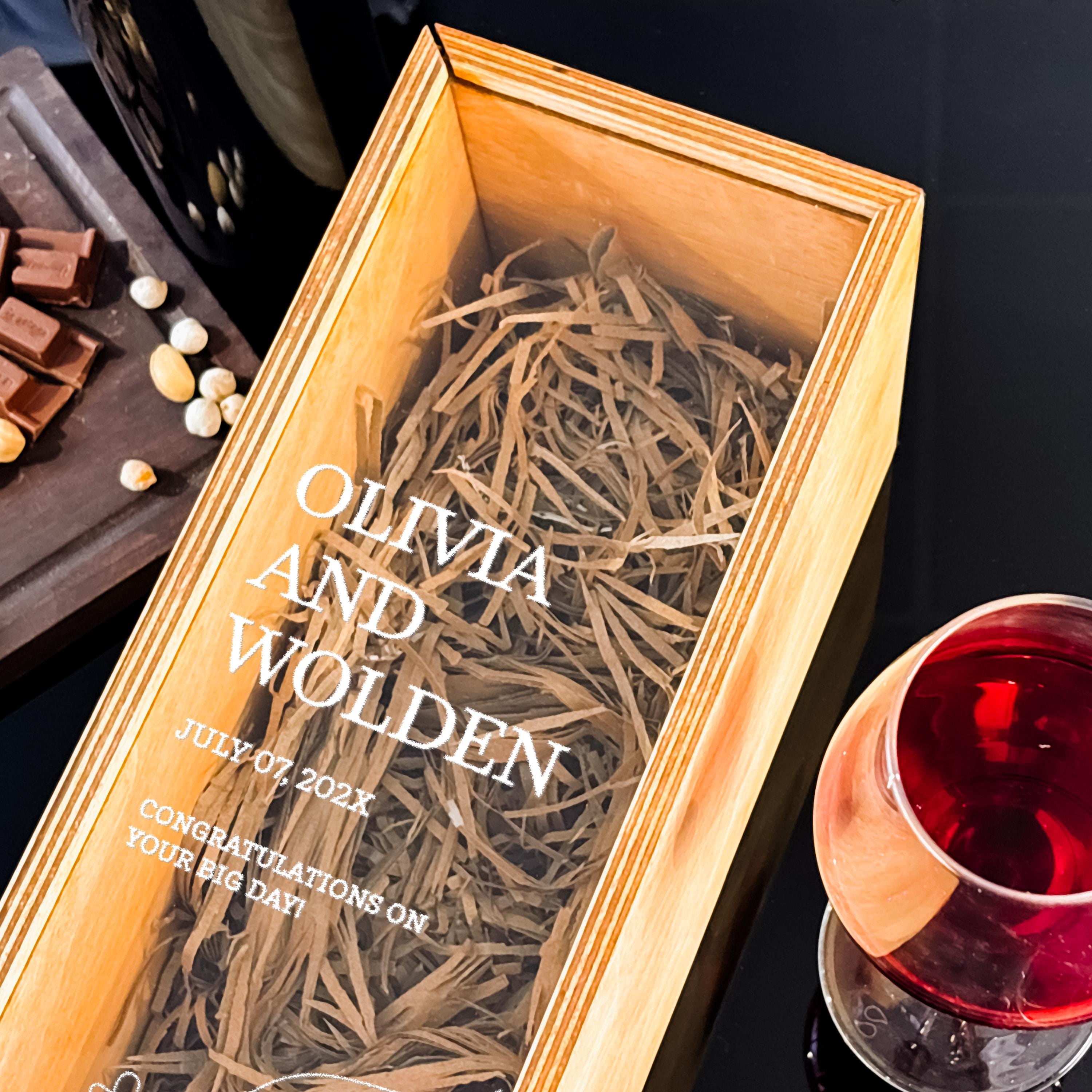 a wooden box with a glass of red wine and a plate of chocolate on a table.