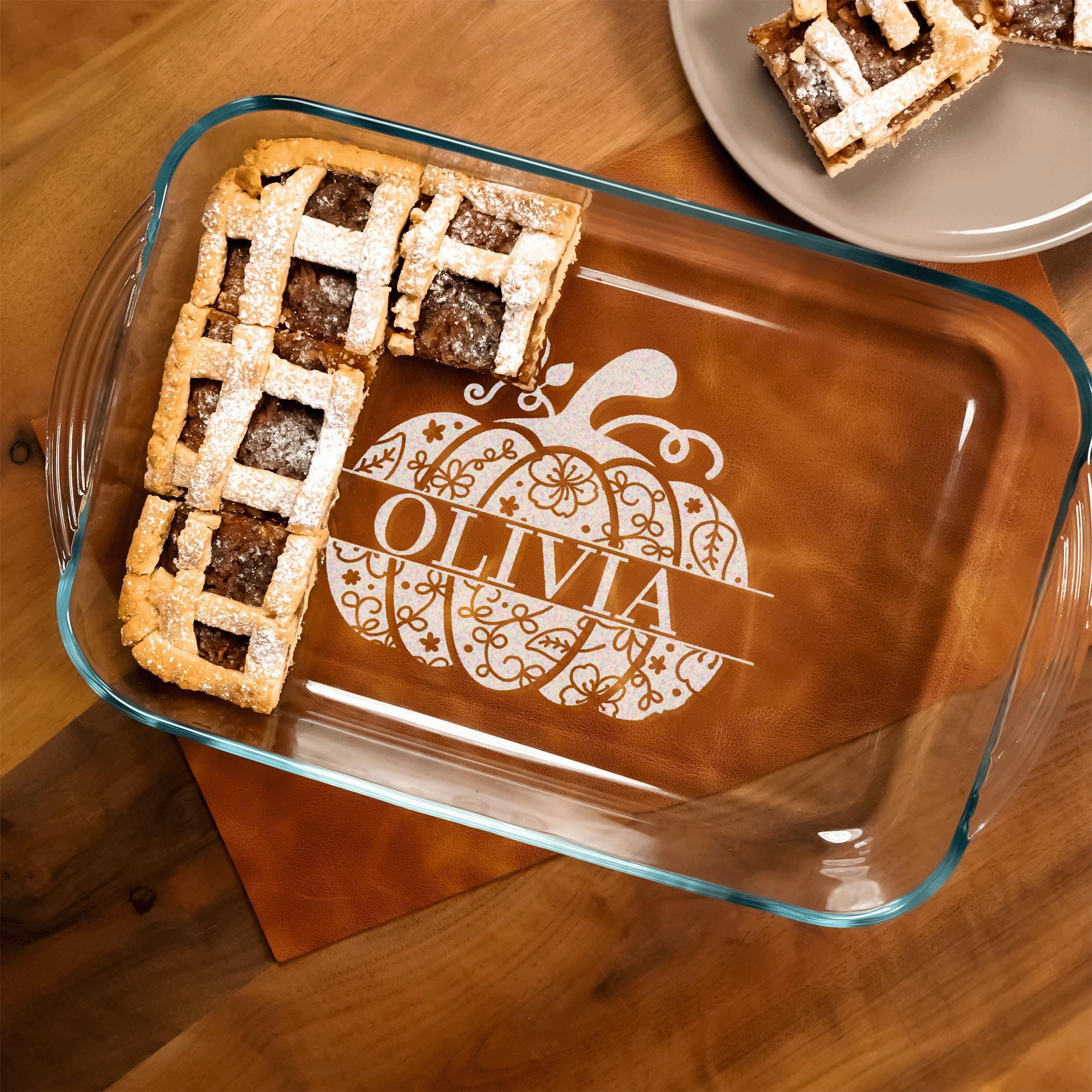 A glass baking dish with a pumpkin-themed design and the name "Olivia" printed on it, containing a slice of pie.