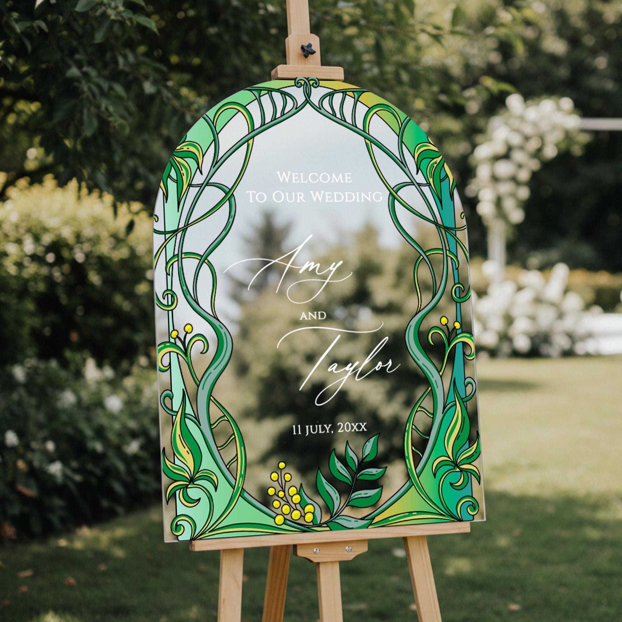 a wooden easel with a decorative sign that reads "Welcome to our wedding Amy and Taylor 11 July, 20XX" in a garden setting.