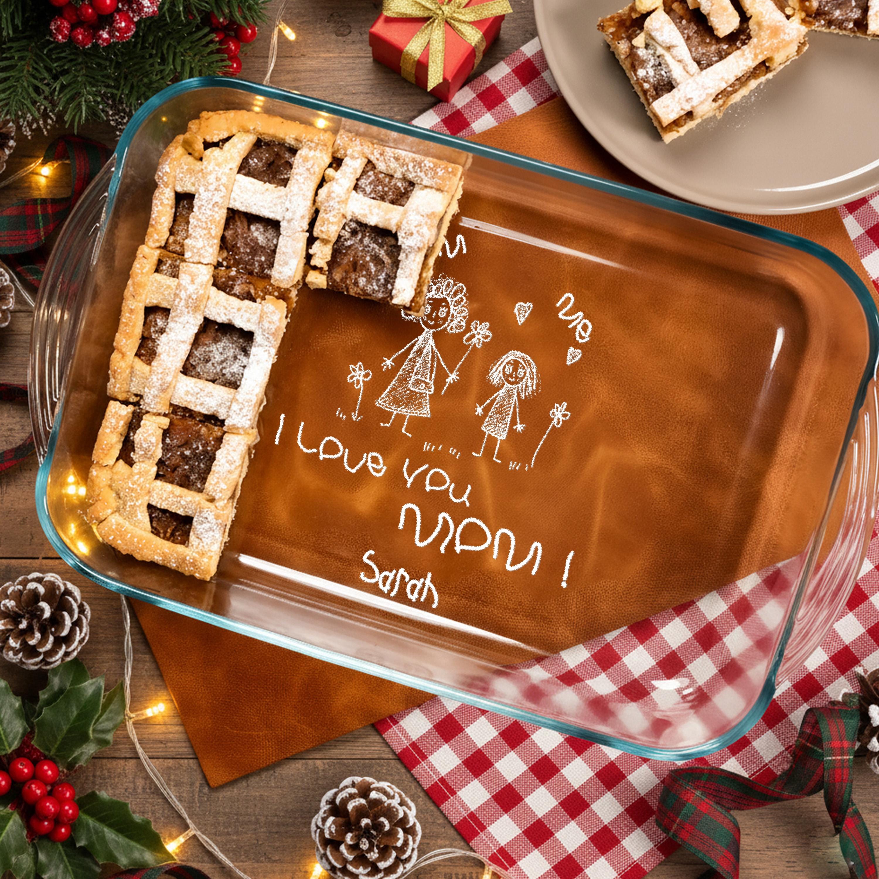 A glass baking dish with a handwritten message, surrounded by holiday decorations and a plate of cookies.