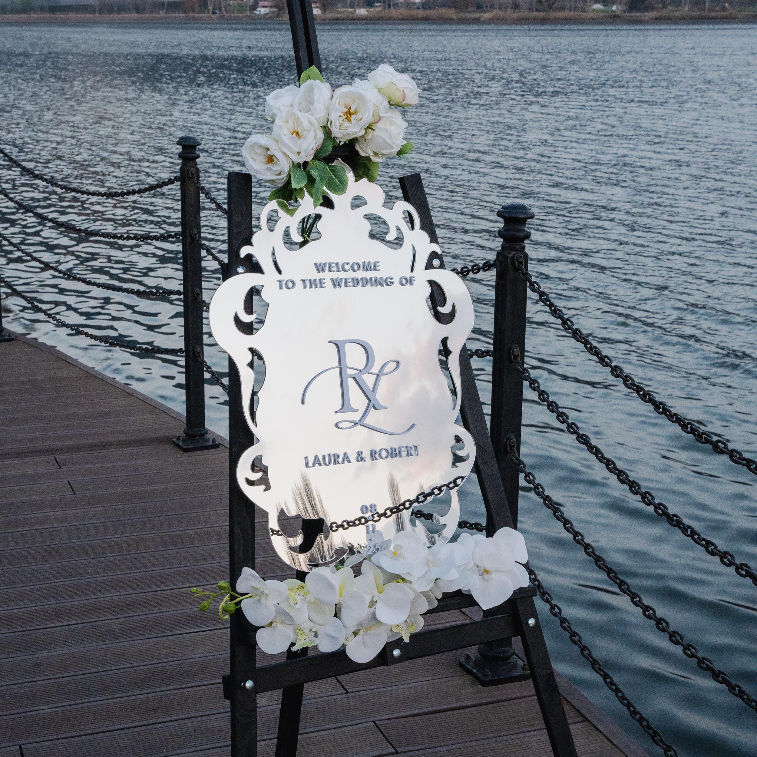 Luxurious silver mirror acrylic wedding welcome sign with intricate baroque-style cutout details and elegant 3D lettering. Featuring the couple’s initials, names, and wedding message, this ornate and sophisticated design adds a regal touch to any wedding entrance.
