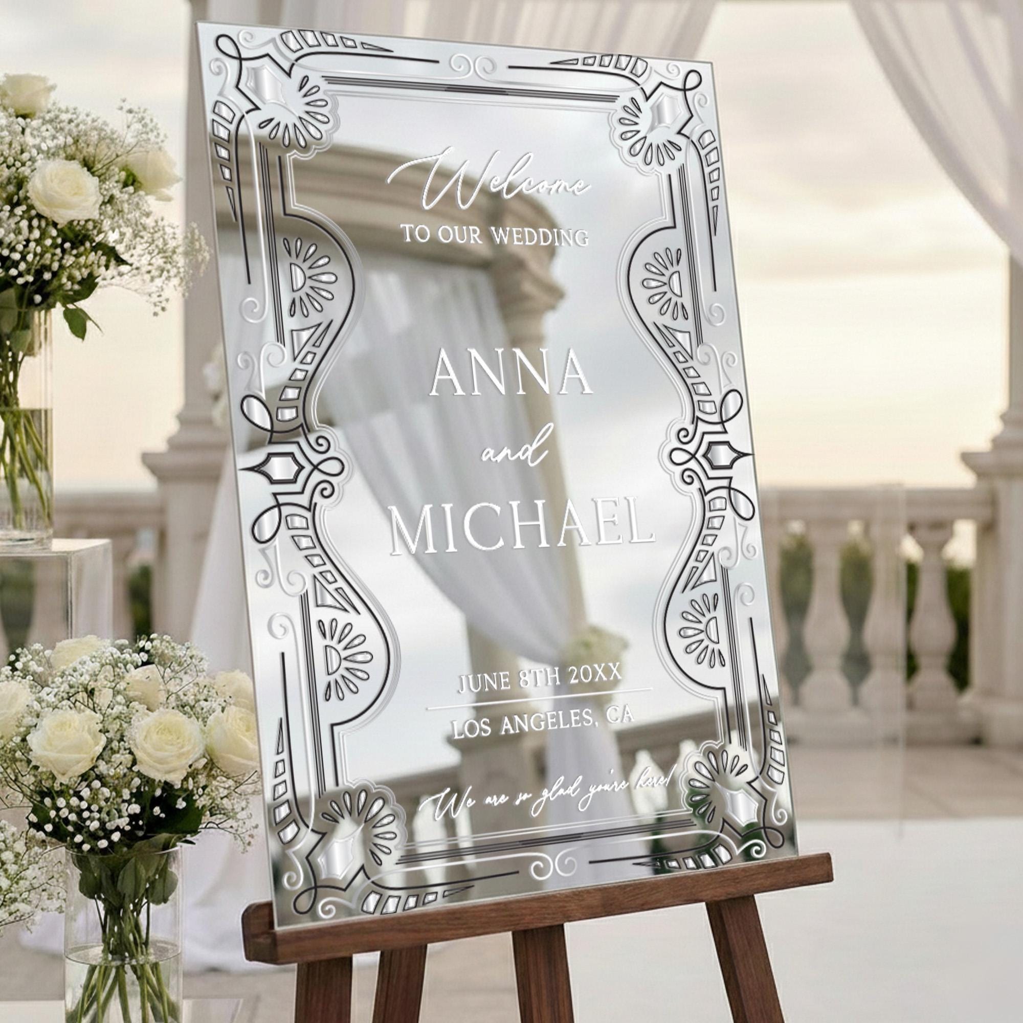 a wedding invitation sign with the names 'Anna and Michael' on it, placed on a wooden stand in front of a wedding venue.