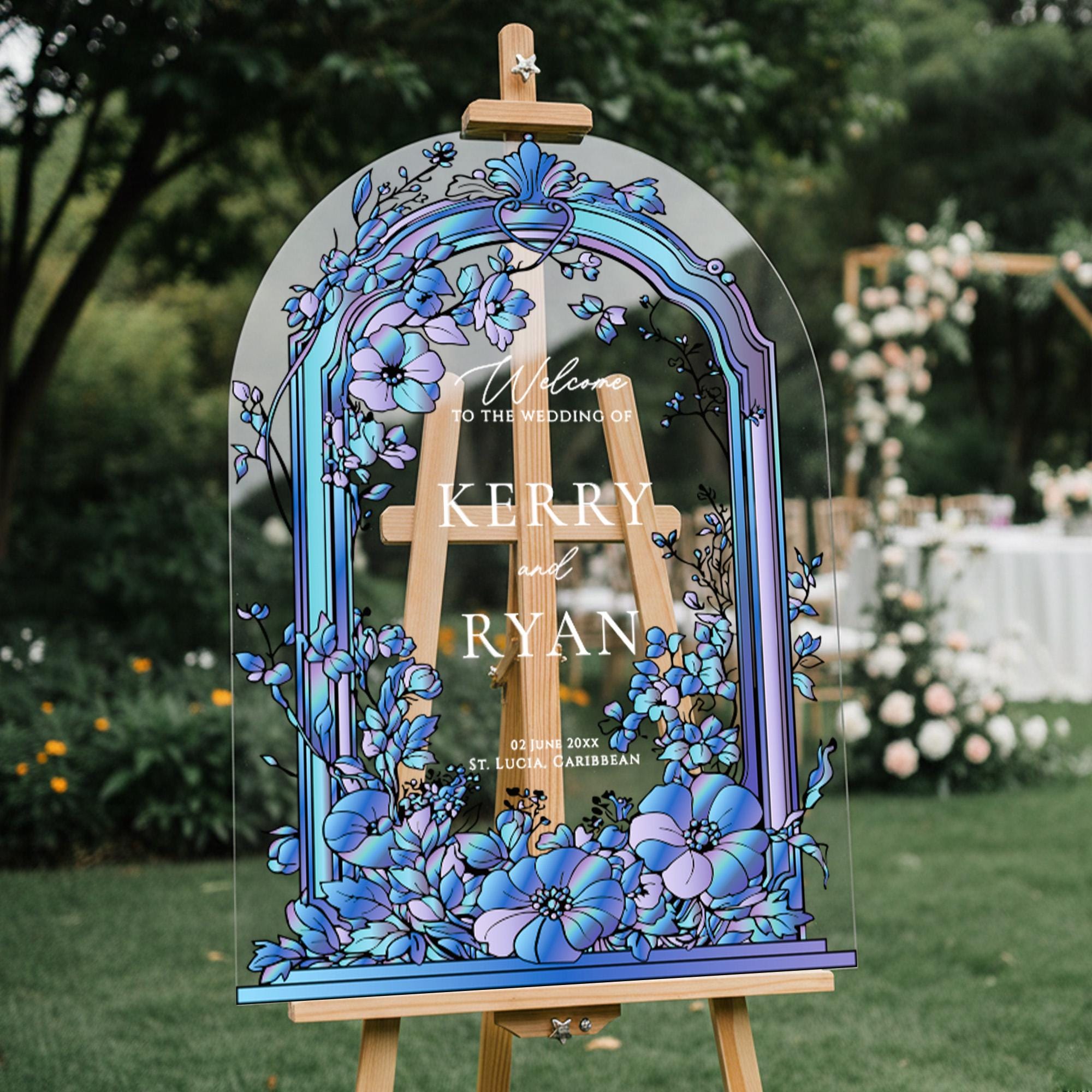 a wooden easel with a colorful, floral-themed sign that reads "Welcome to the Wedding of KERRY and RYAN".