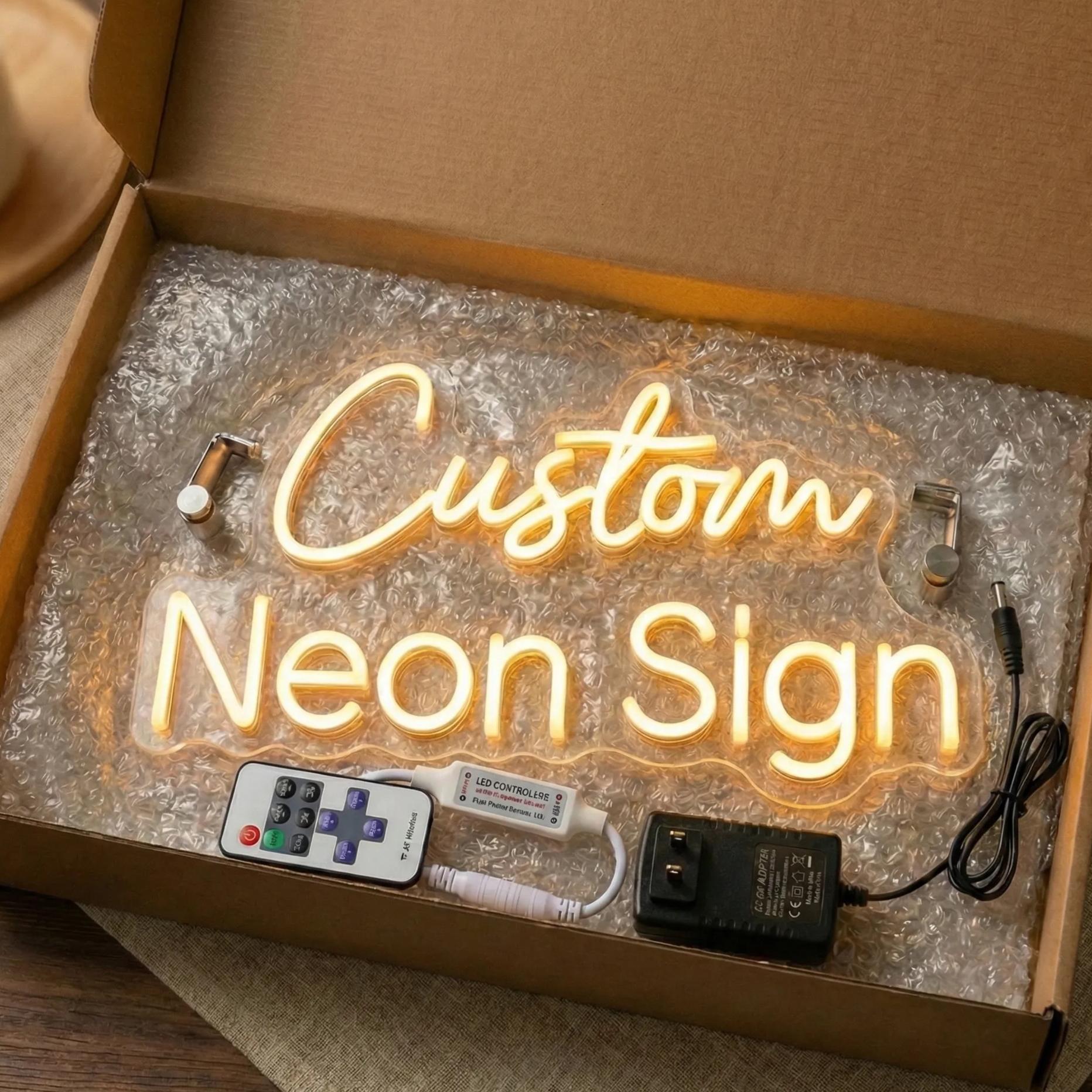 A cardboard box containing a custom neon sign, a remote control, and a power adapter.