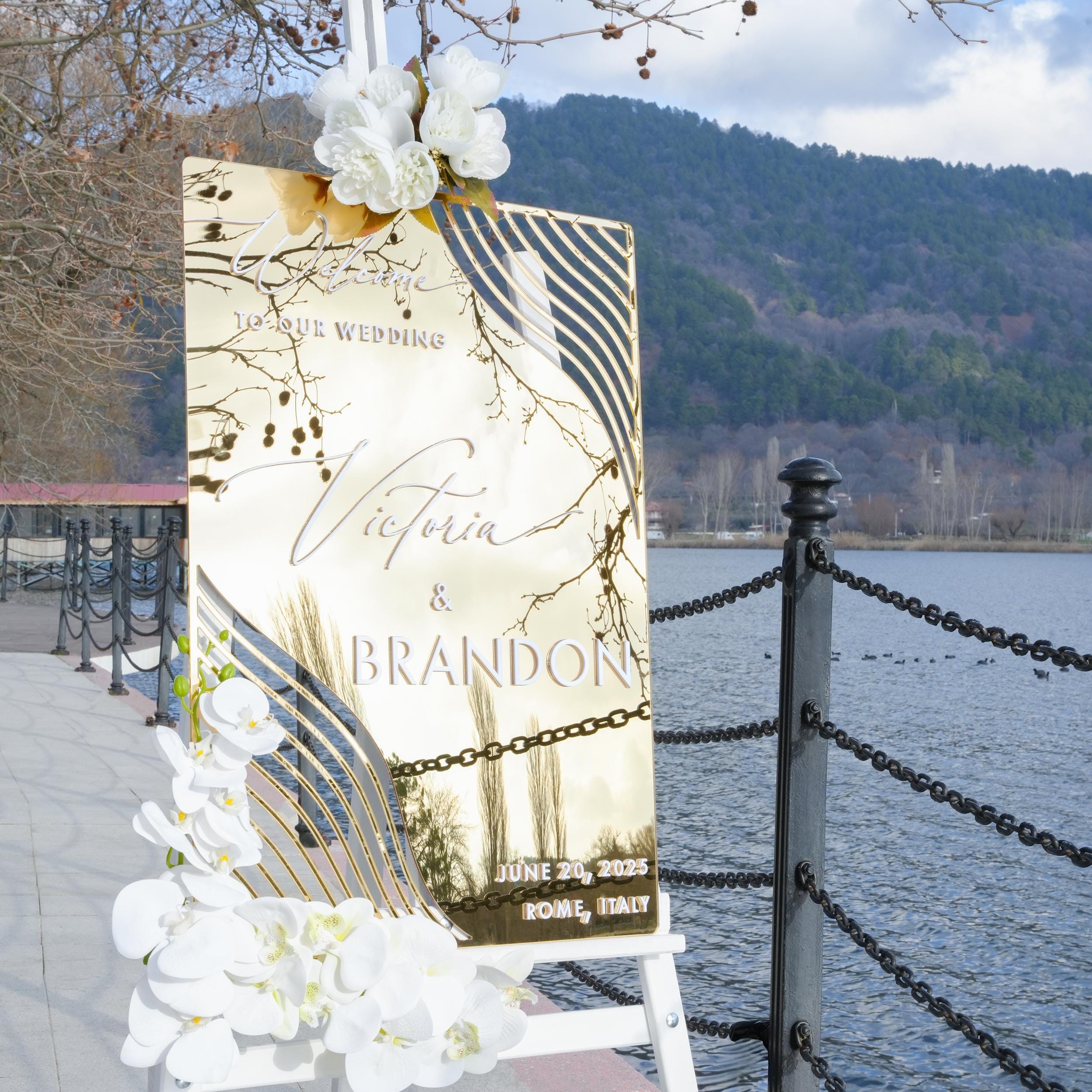 gold mirror acrylic wedding welcome sign with elegant 3D lettering, featuring the couple's names and wedding details. The reflective surface and contemporary design add a sophisticated and glamorous touch to any wedding entrance.