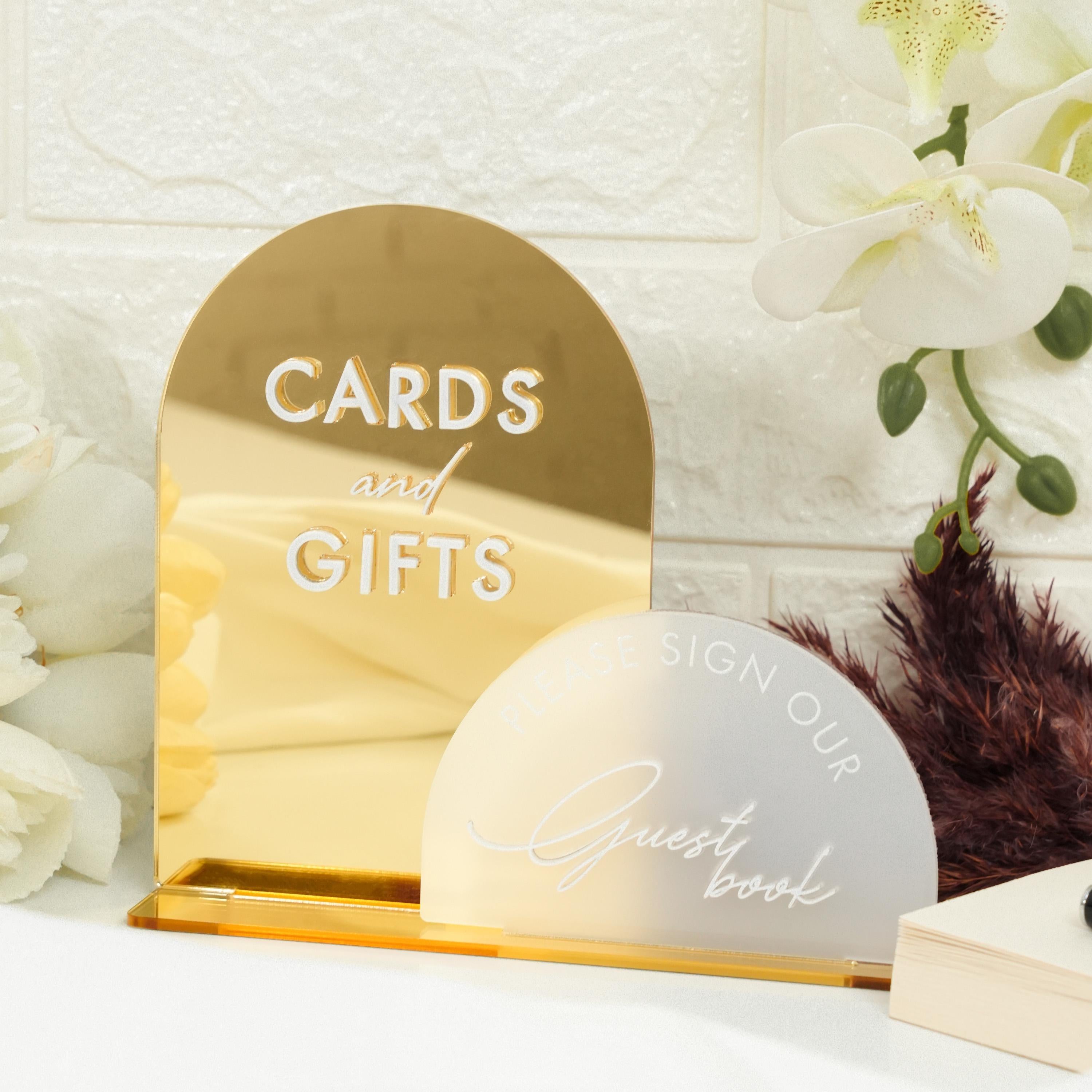 a gold card and gift box next to a white flower