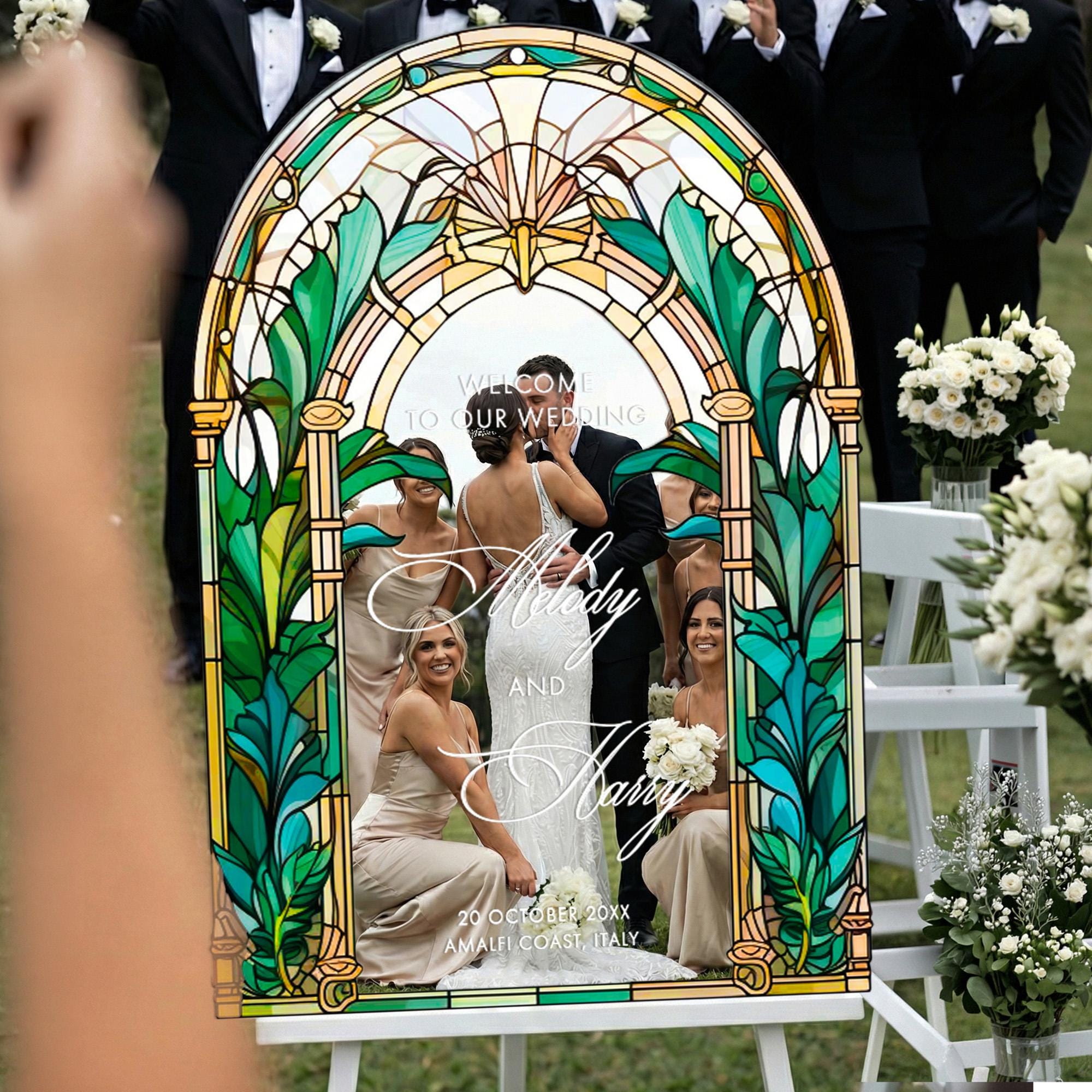 a stained glass-style wedding sign with a bride and groom photo, surrounded by flower arrangements and other wedding decorations.