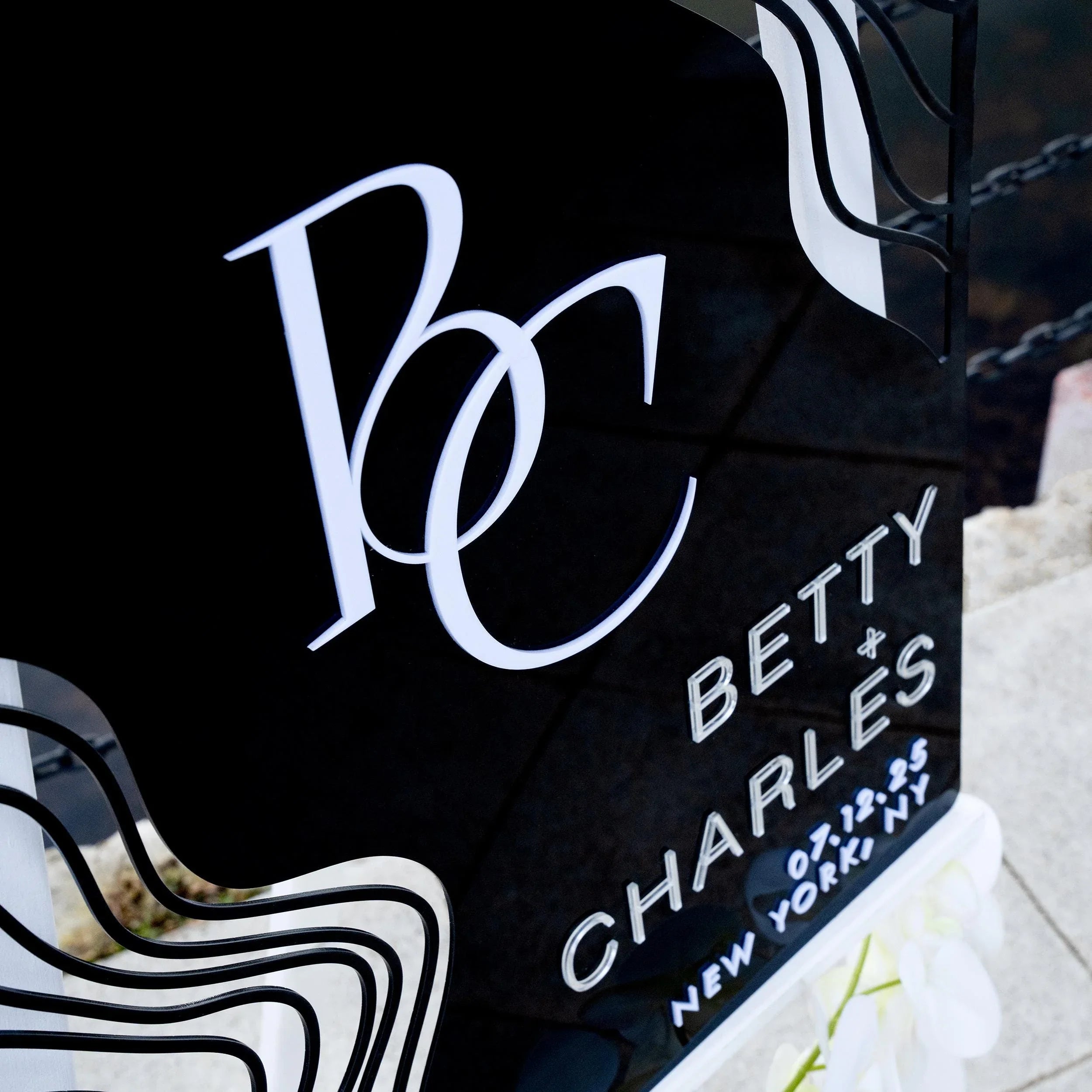 Boho black acrylic wedding welcome sign with striking 3D lettering, featuring the couple’s initials, names, and wedding date. The sleek design and artistic wavy accents create a stylish, contemporary focal point at any wedding entrance.