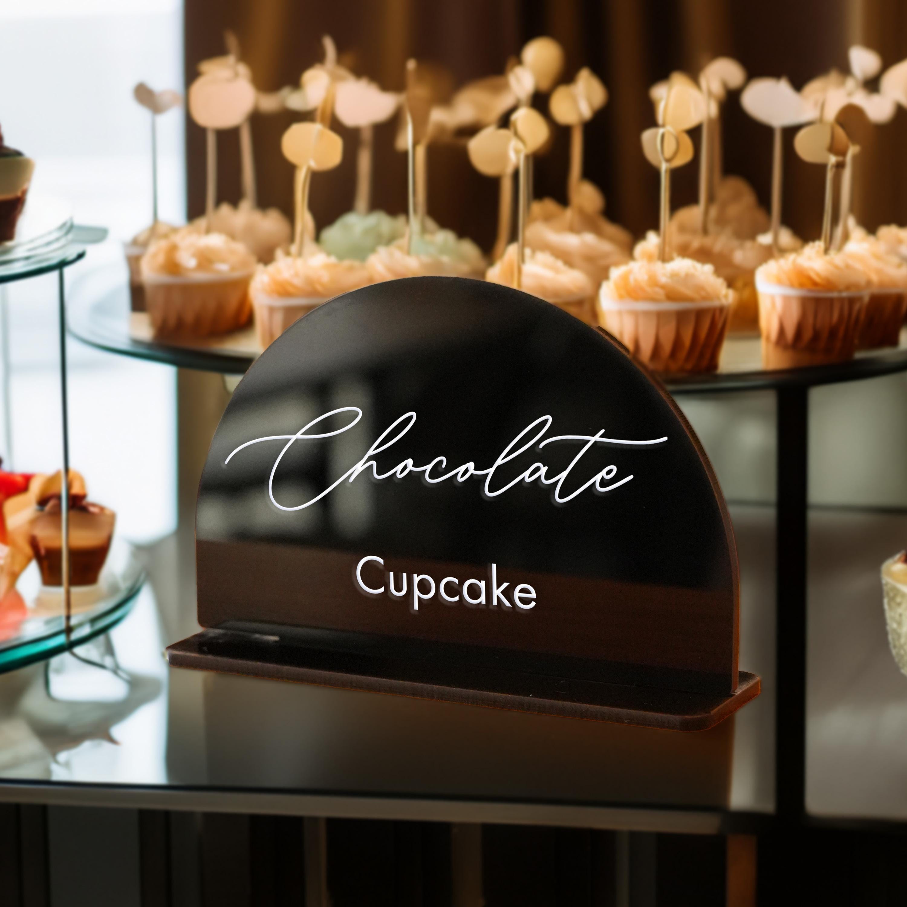 a display of cupcakes on a table with a sign that says chocolate cup