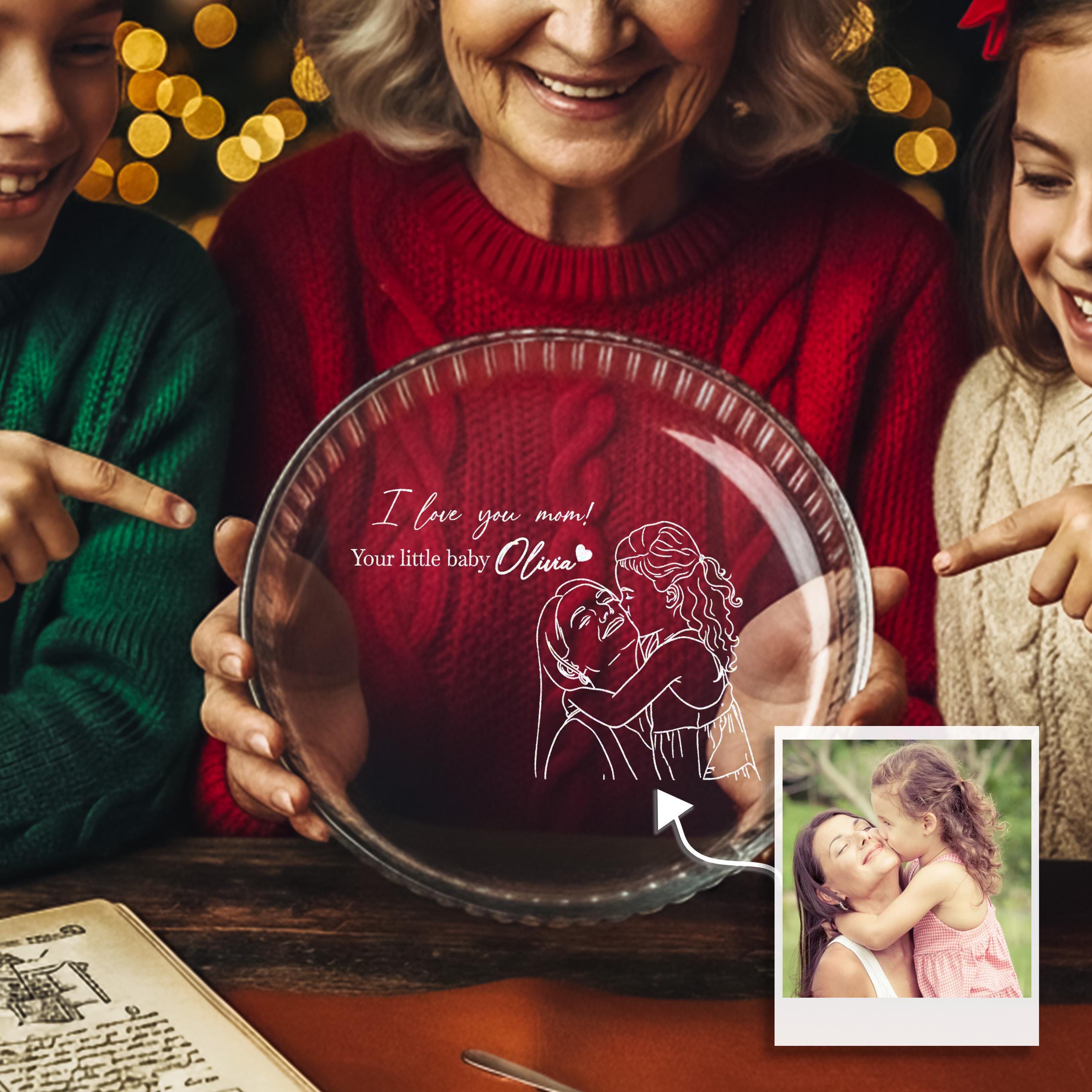An elderly woman holding a glass plate with a drawing of two women embracing, surrounded by other people.