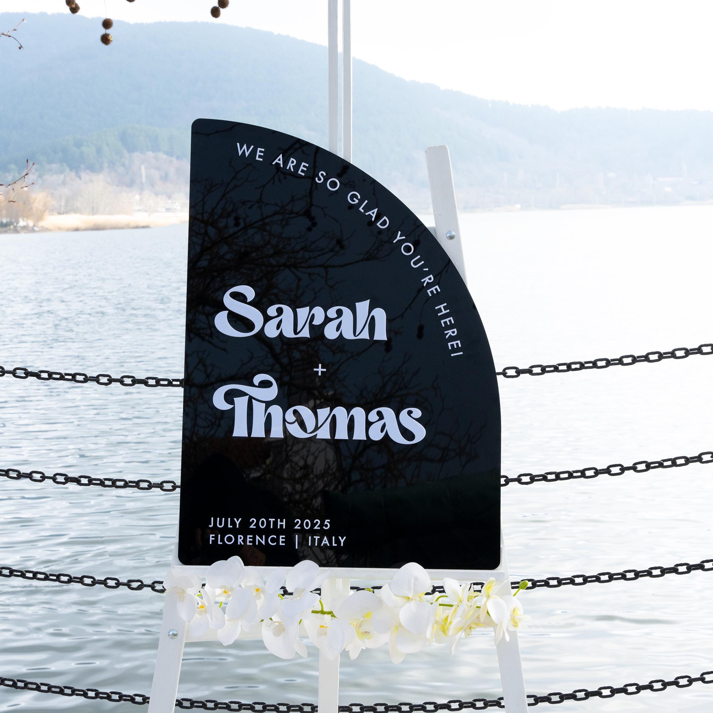 Modern black acrylic wedding welcome sign with bold 3D lettering, featuring the couples names and wedding details. The unique curved design adds a contemporary and stylish touch to any wedding entrance.