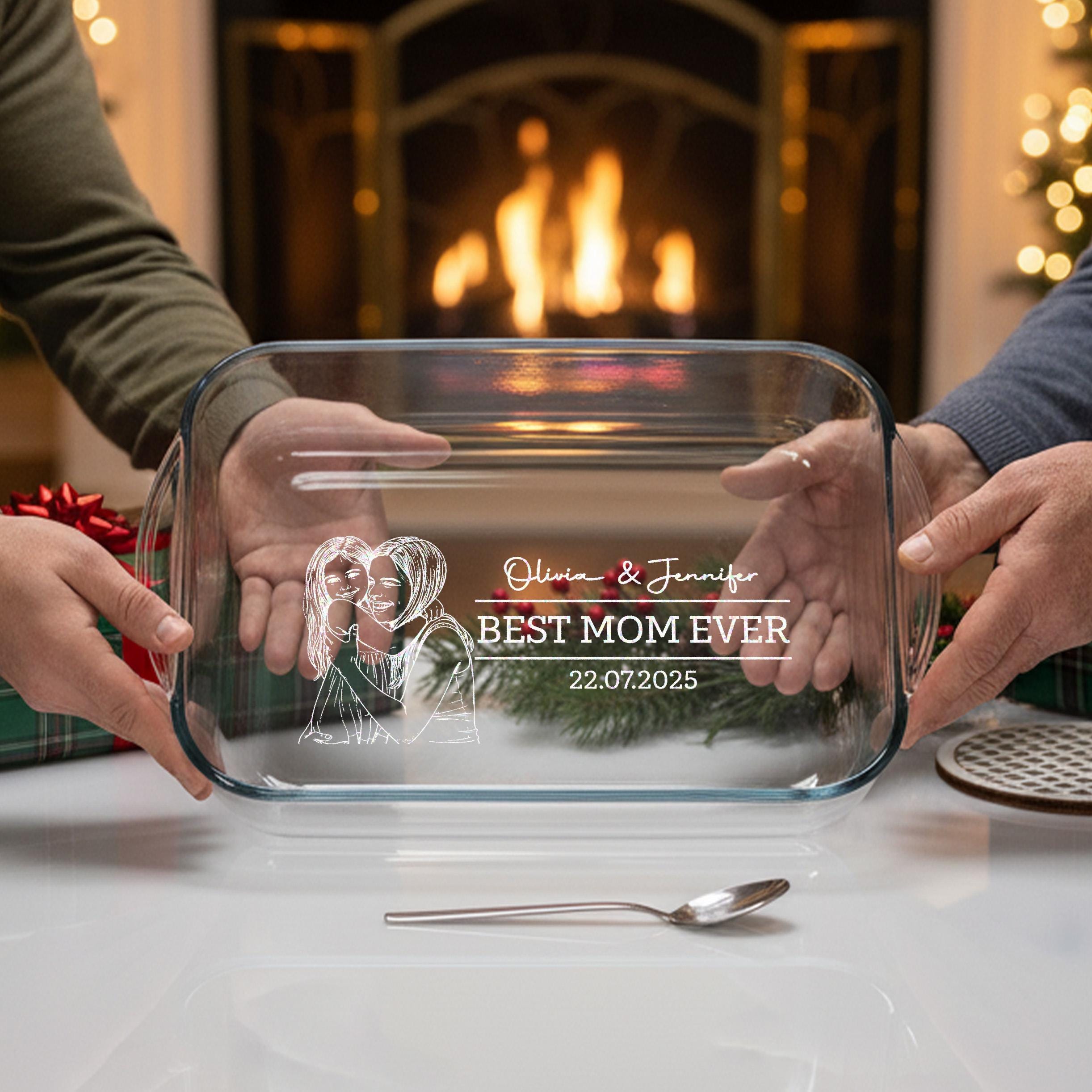 A person is holding a clear glass dish with a personalized message engraved on it, in front of a fireplace.