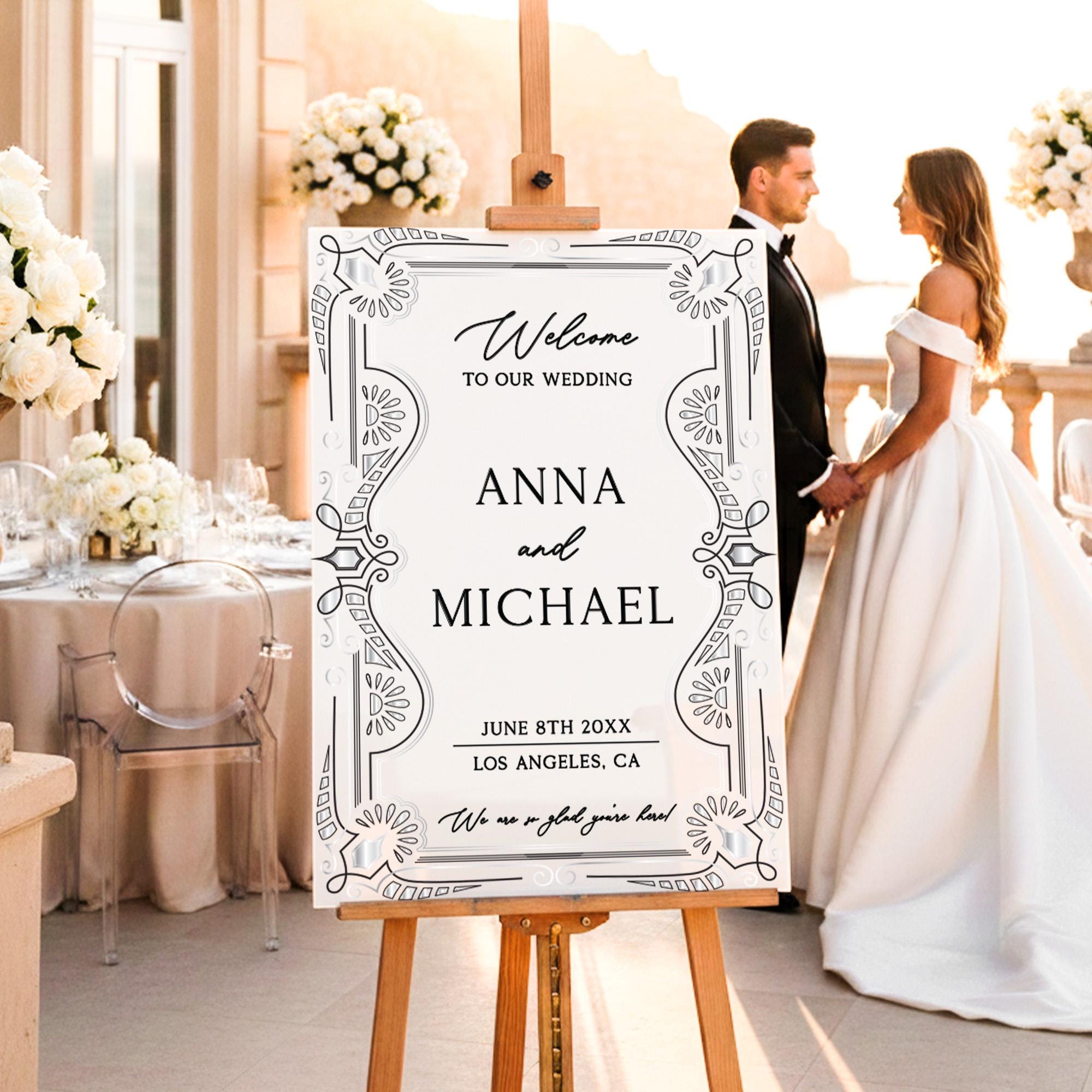 a couple standing in front of a wedding sign that reads "Welcome to our wedding Anna and Michael June 8th 20XX Los Angeles, CA We are a great couple!"