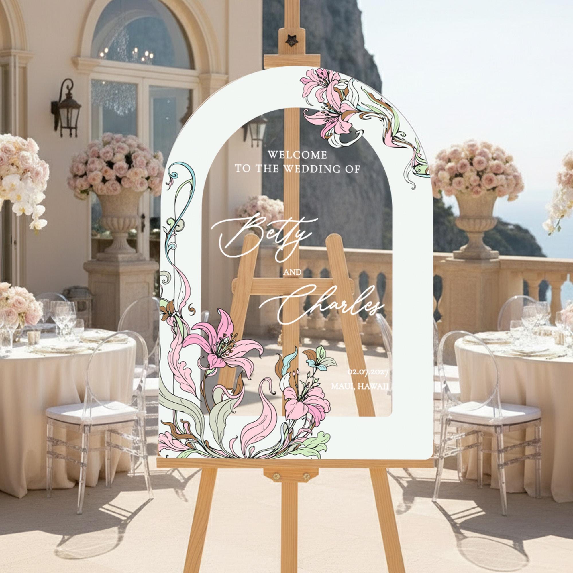 a wedding invitation with a floral design, placed on a wooden easel in a setting with tables and chairs.