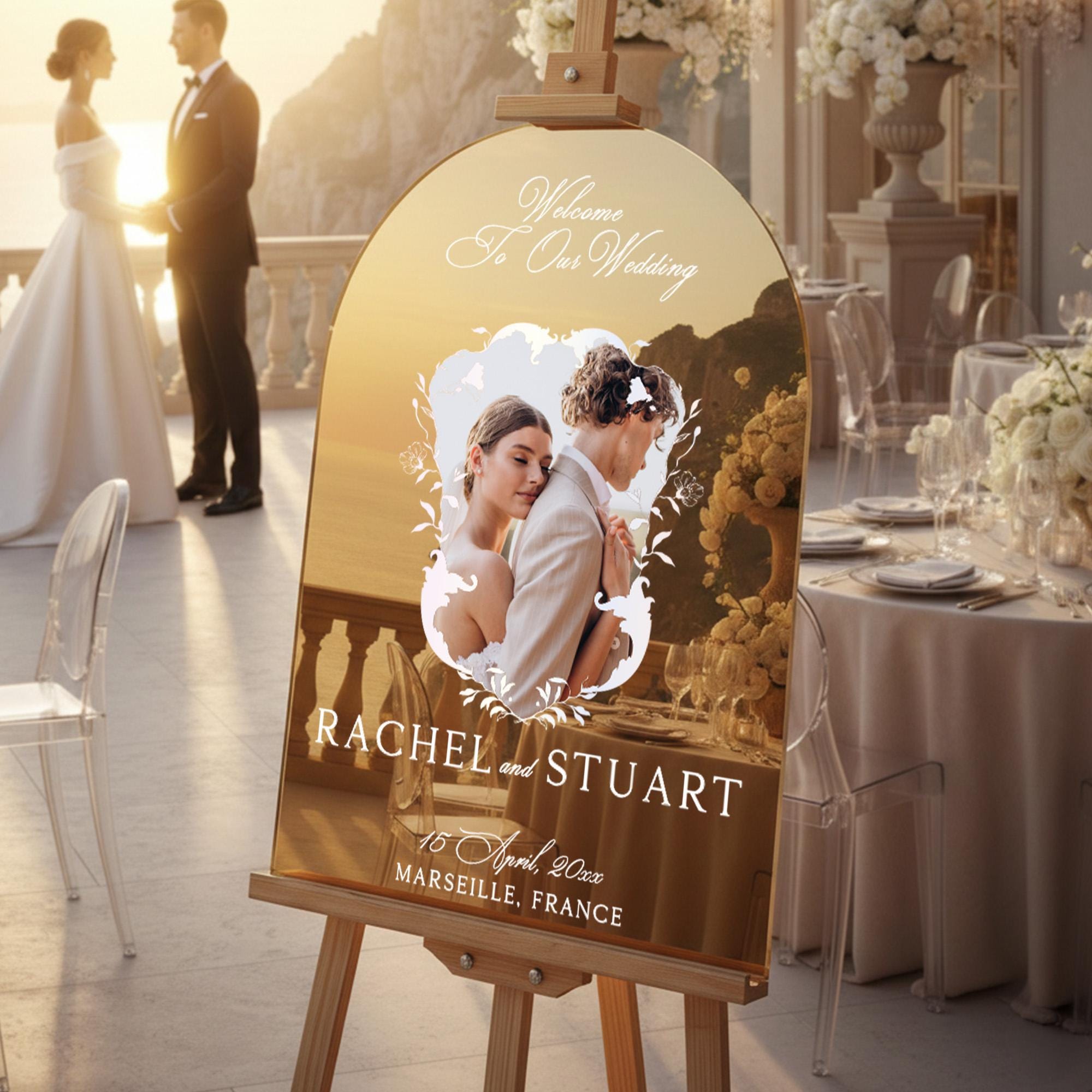 a wedding invitation sign with a couple's photo, placed on a wooden easel in a formal setting.