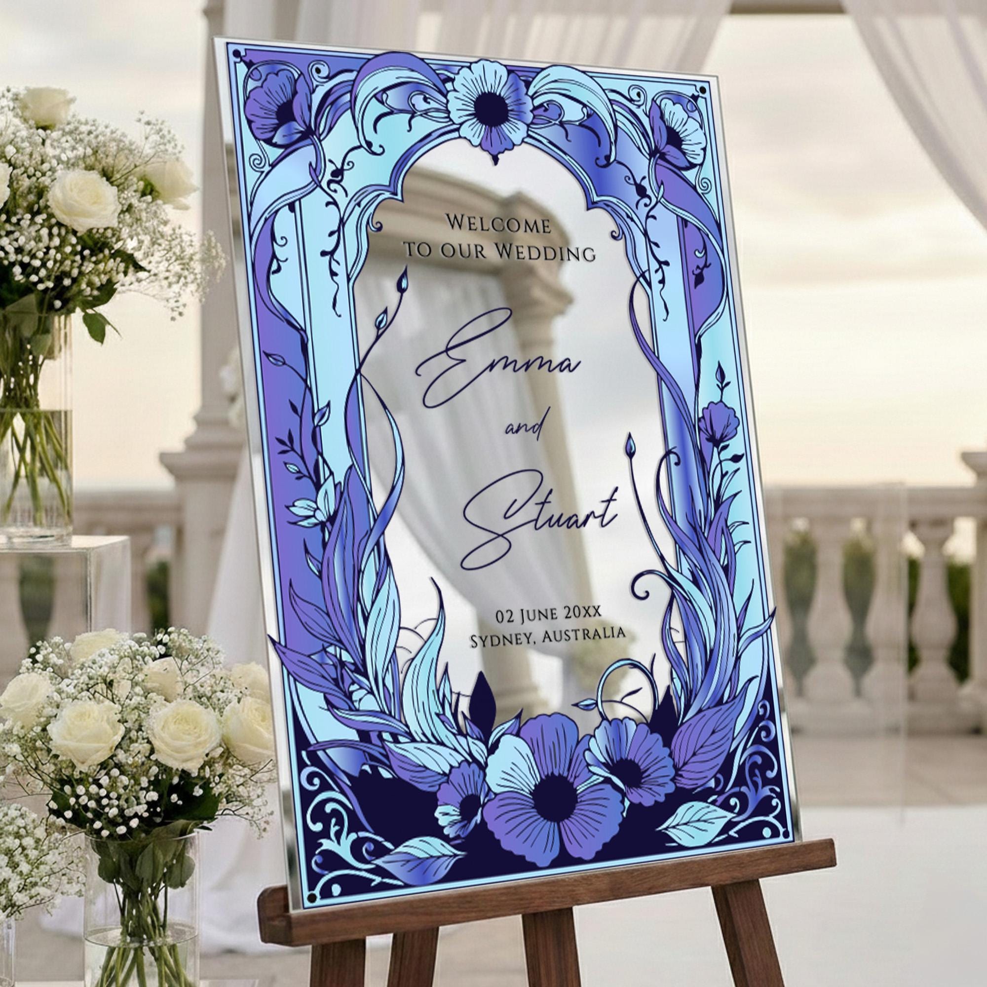 a wedding invitation with a blue and white floral design, placed on a wooden easel.