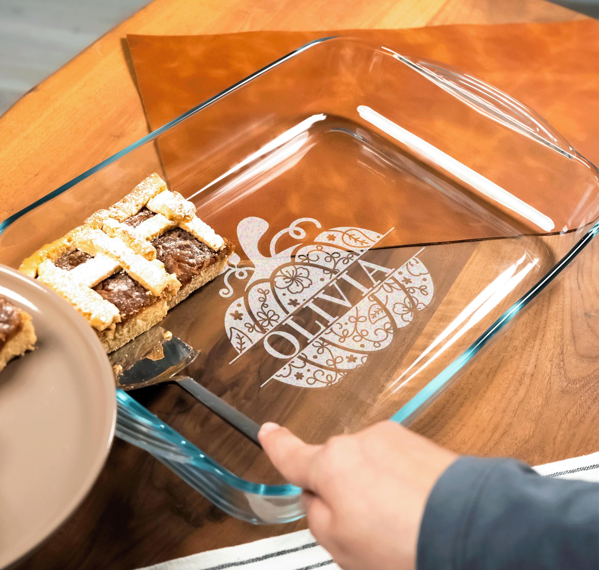 A person is cutting a pie into a glass casserole dish with a pumpkin design on it.